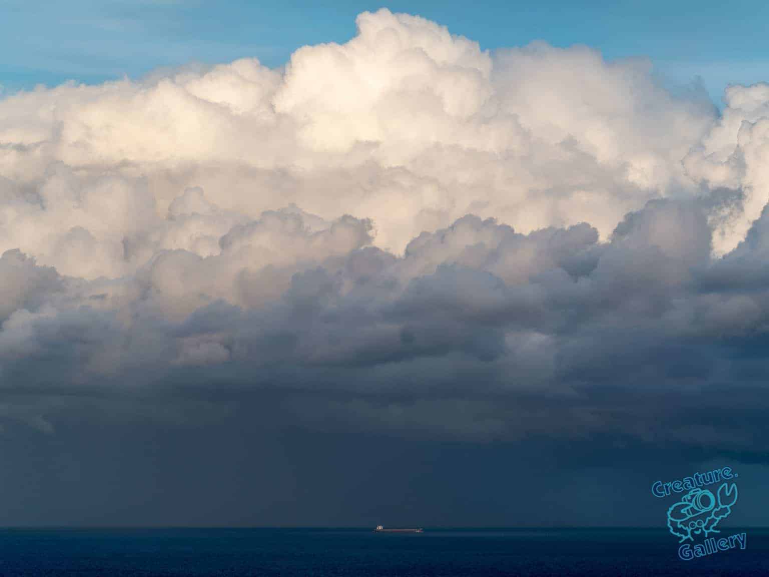 Oil tanker in the ocean in front of cumulous cloud