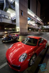 Tuk tuk passes a Porsche